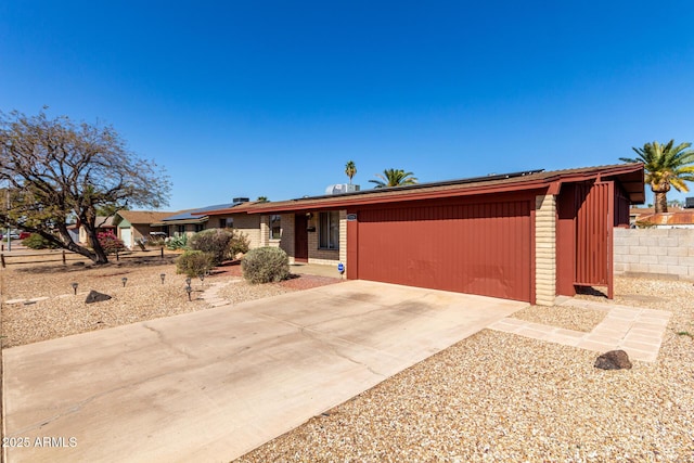 view of front of property with concrete driveway and solar panels