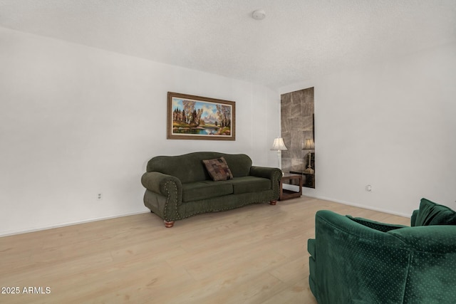 living area with light wood finished floors, baseboards, and a textured ceiling