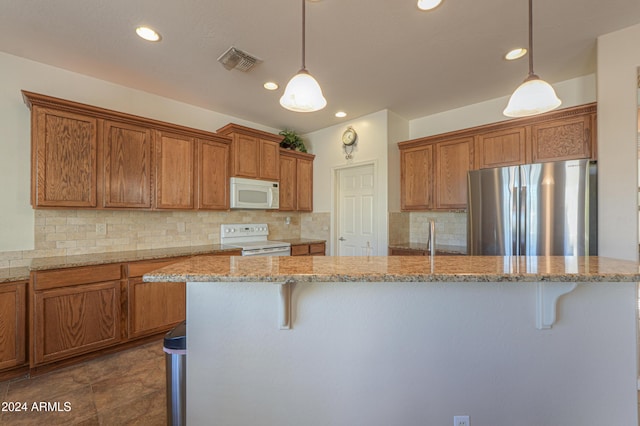 kitchen with light stone countertops, backsplash, a breakfast bar, white appliances, and pendant lighting