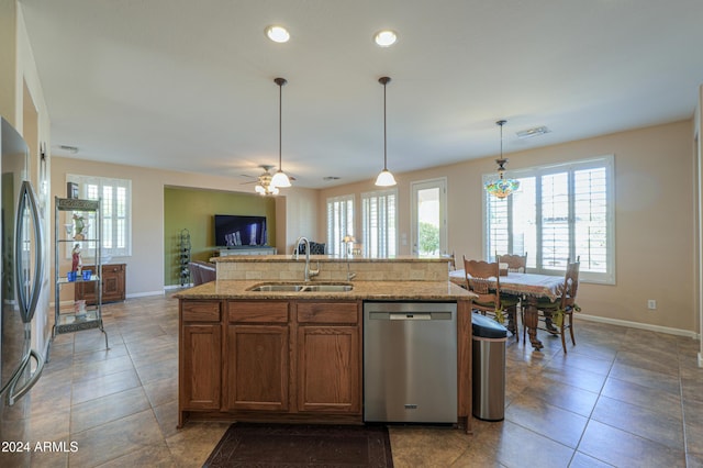 kitchen featuring stainless steel appliances, ceiling fan, a kitchen island with sink, sink, and pendant lighting