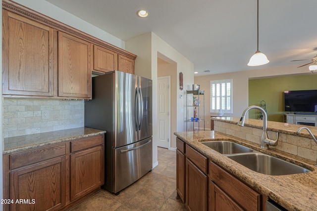 kitchen featuring decorative backsplash, appliances with stainless steel finishes, light stone counters, sink, and decorative light fixtures