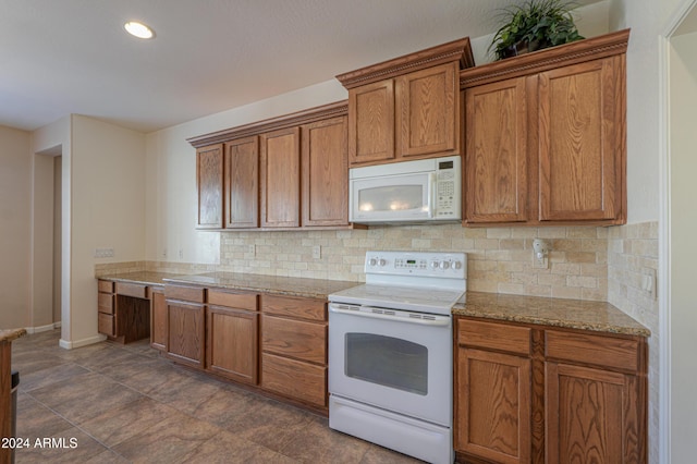 kitchen with light stone countertops, white appliances, and backsplash