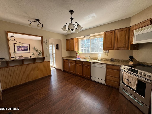 kitchen featuring an inviting chandelier, hanging light fixtures, white appliances, and dark hardwood / wood-style floors