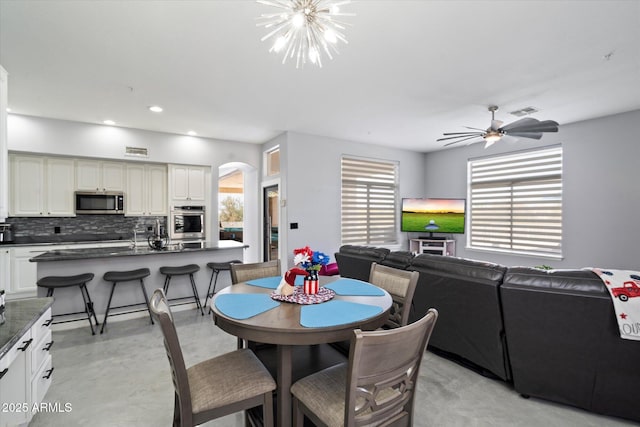 dining space featuring ceiling fan with notable chandelier