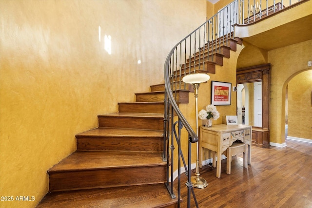1614 Palmcroft Dr SW, Phoenix, AZ 85007 - stairway featuring wood finished floors, arched walkways, a towering ceiling, and baseboards