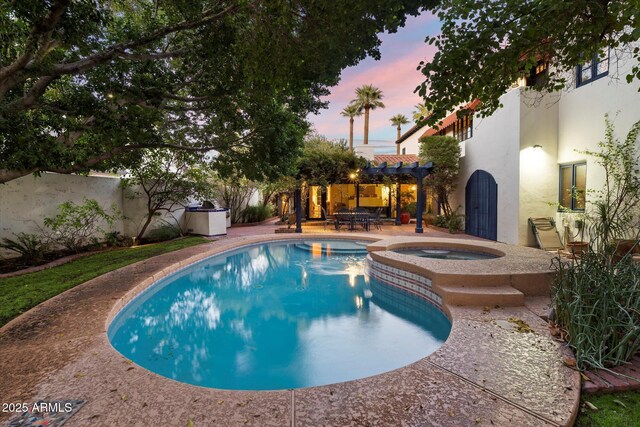 1614 Palmcroft Dr SW, Phoenix, AZ 85007 - pool at dusk with a patio area, a fenced backyard, a pergola, and a pool with connected hot tub