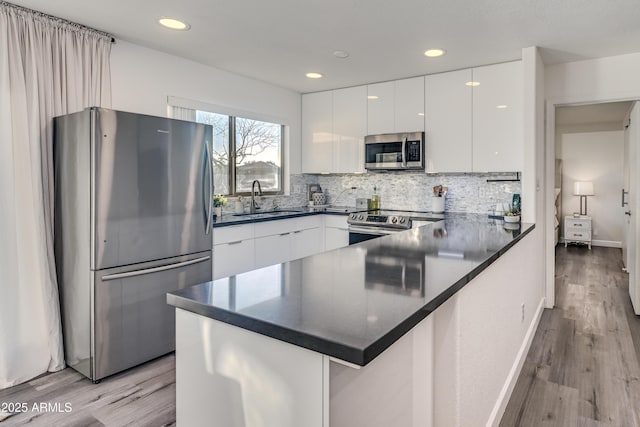 kitchen featuring a sink, dark countertops, modern cabinets, and stainless steel appliances