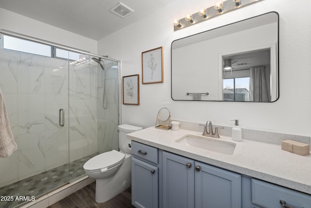 bathroom featuring a wealth of natural light, toilet, vanity, visible vents, and a marble finish shower