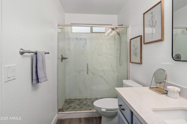 full bath with wood finished floors, a marble finish shower, toilet, and vanity
