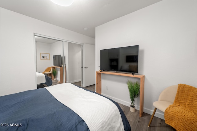 bedroom with a closet, wood finished floors, and baseboards