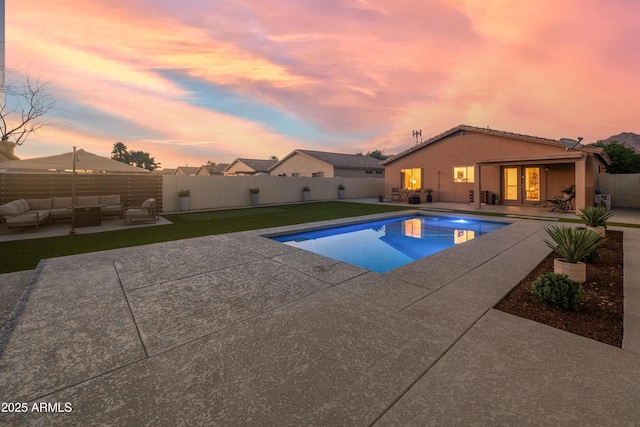 pool at dusk featuring a patio, an outdoor living space, a fenced in pool, and a fenced backyard