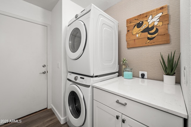 laundry room with dark wood-style flooring, stacked washer and clothes dryer, cabinet space, and baseboards