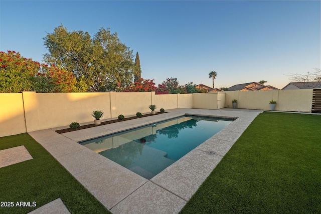 pool at dusk with a lawn, a fenced in pool, and a fenced backyard