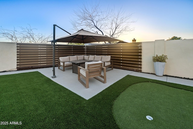yard at dusk with outdoor lounge area, a fenced backyard, and a patio area