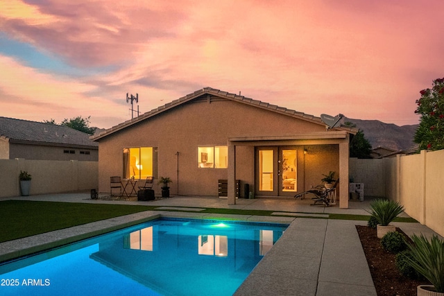 rear view of house featuring a fenced backyard, stucco siding, a fenced in pool, a patio area, and french doors
