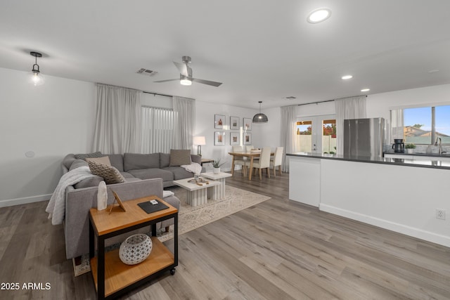 living area featuring recessed lighting, light wood-style floors, ceiling fan, visible vents, and baseboards