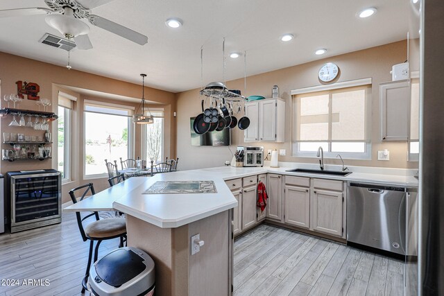 kitchen with dishwasher, kitchen peninsula, sink, ceiling fan, and light wood-type flooring