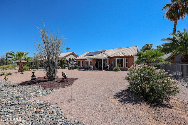 back of property featuring solar panels and a patio area