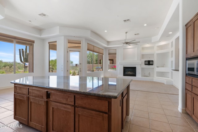 22463 N 54th St, Phoenix, AZ 85054 - kitchen with light tile patterned floors, ceiling fan, built in features, a kitchen island, and stainless steel microwave