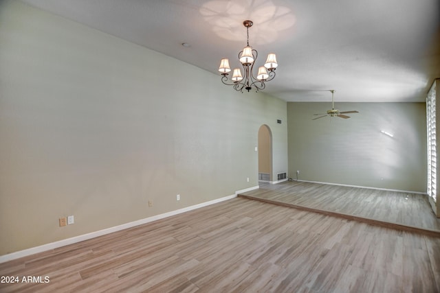 empty room with lofted ceiling, ceiling fan with notable chandelier, and light wood-type flooring