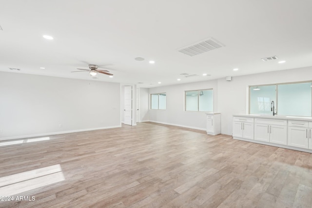 unfurnished living room featuring light hardwood / wood-style floors, ceiling fan, and sink