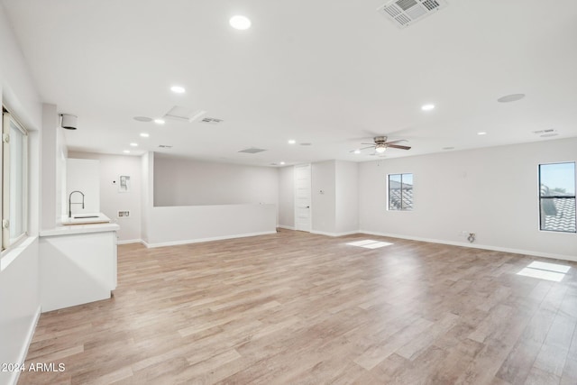 spare room featuring a wealth of natural light, sink, ceiling fan, and light hardwood / wood-style flooring