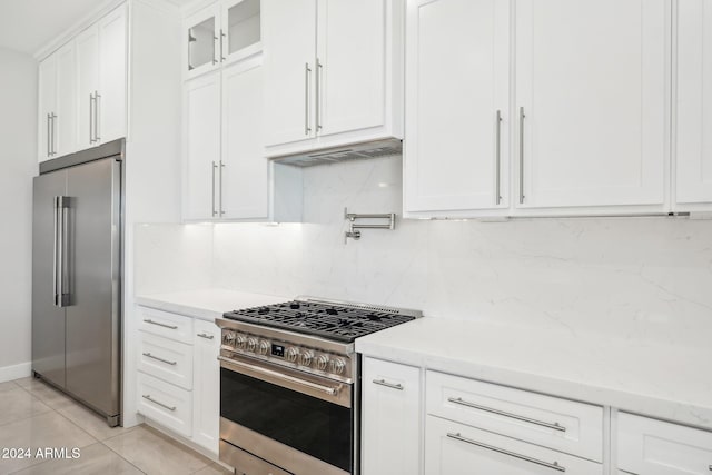 kitchen featuring white cabinets, high quality appliances, light stone counters, and decorative backsplash