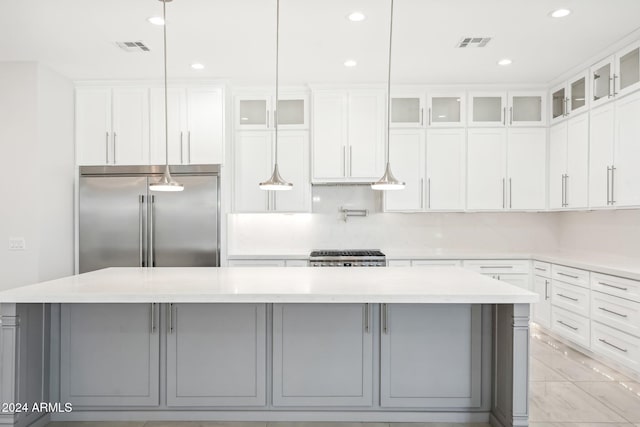 kitchen with white cabinetry, appliances with stainless steel finishes, decorative light fixtures, light stone countertops, and a spacious island