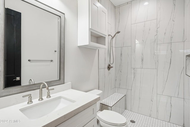 bathroom with toilet, vanity, and a tile shower