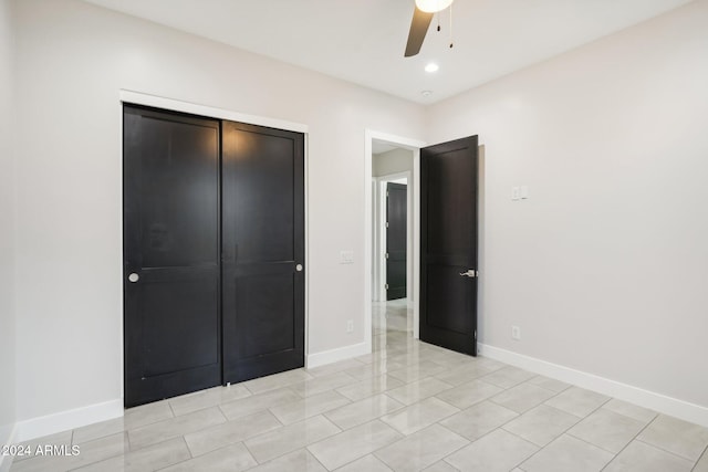 unfurnished bedroom with light tile patterned floors, ceiling fan, and a closet