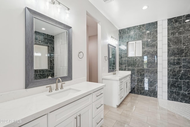 bathroom with tile walls, tile patterned flooring, vanity, and a tile shower