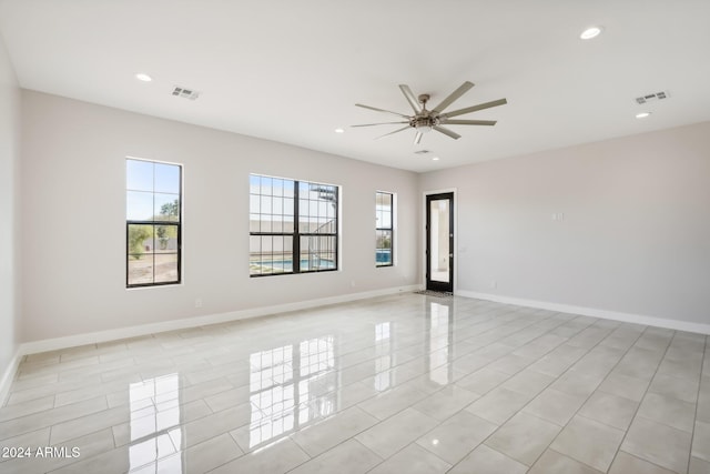 tiled empty room featuring a wealth of natural light and ceiling fan