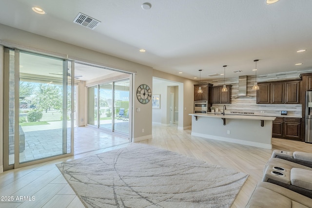841 E Farmers Ln, Queen Creek, AZ 85140 - kitchen featuring wall chimney exhaust hood, a kitchen breakfast bar, appliances with stainless steel finishes, backsplash, and light countertops