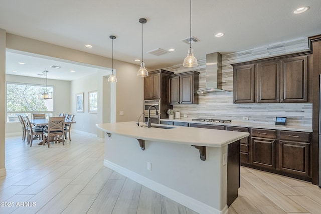 841 E Farmers Ln, Queen Creek, AZ 85140 - kitchen featuring wall chimney exhaust hood, a sink, light countertops, a kitchen breakfast bar, and decorative backsplash
