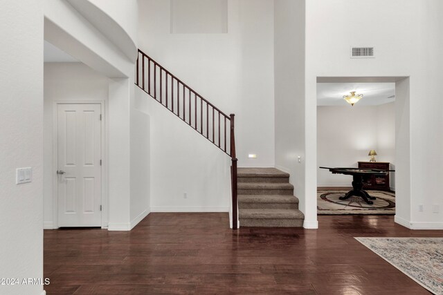 stairs featuring a towering ceiling and hardwood / wood-style flooring