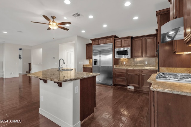 kitchen featuring dark hardwood / wood-style flooring, ventilation hood, sink, built in appliances, and an island with sink