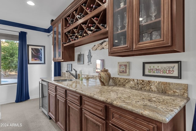 bar with light stone countertops, light colored carpet, beverage cooler, and sink