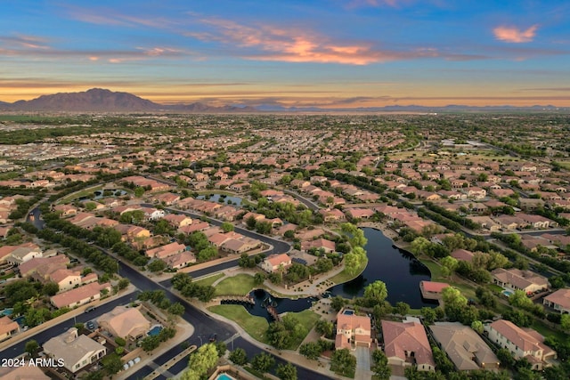 aerial view at dusk featuring a water and mountain view