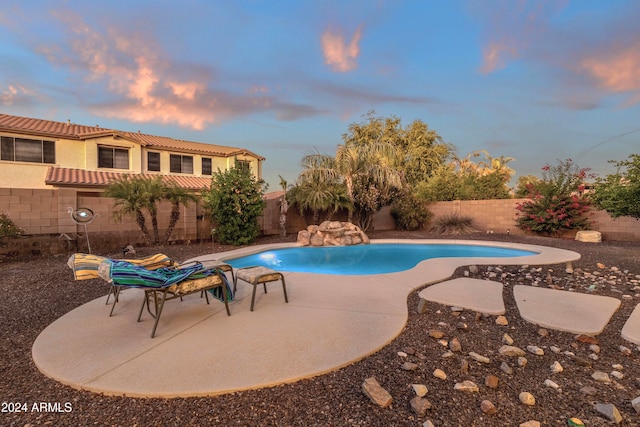 pool at dusk with a patio area and pool water feature