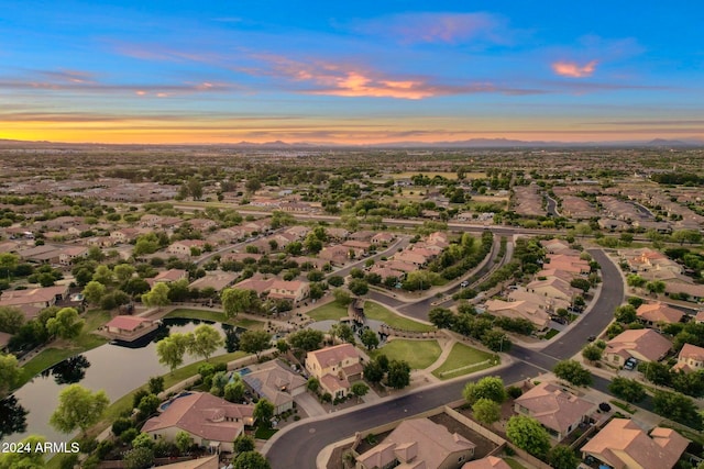 aerial view at dusk featuring a water view