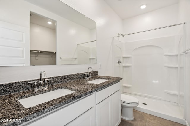 bathroom with tile patterned flooring, a shower, vanity, and toilet