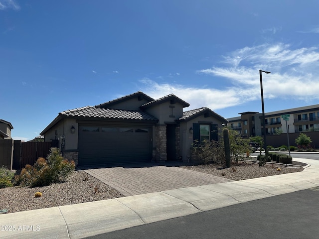15301 W Moreland St, Goodyear, AZ 85338 - view of front of home with stone siding, an attached garage, stucco siding, fence, and decorative driveway
