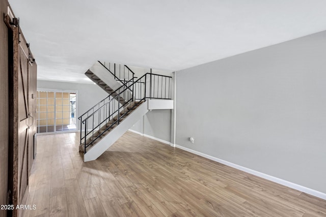 unfurnished living room featuring light wood-type flooring and a barn door