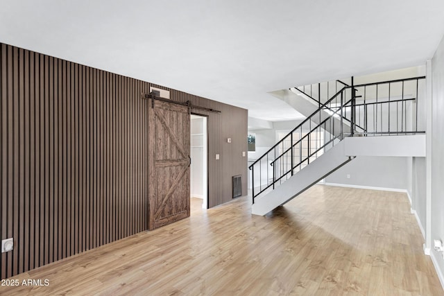 entrance foyer featuring wood walls, a barn door, and light hardwood / wood-style floors