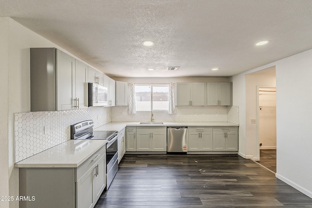 3017 N 46th Dr, Phoenix, AZ 85031 - kitchen with appliances with stainless steel finishes, a sink, light countertops, backsplash, and dark wood finished floors