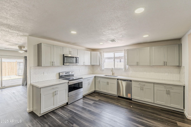 3017 N 46th Dr, Phoenix, AZ 85031 - kitchen with appliances with stainless steel finishes, a sink, a textured ceiling, light countertops, and dark wood-type flooring