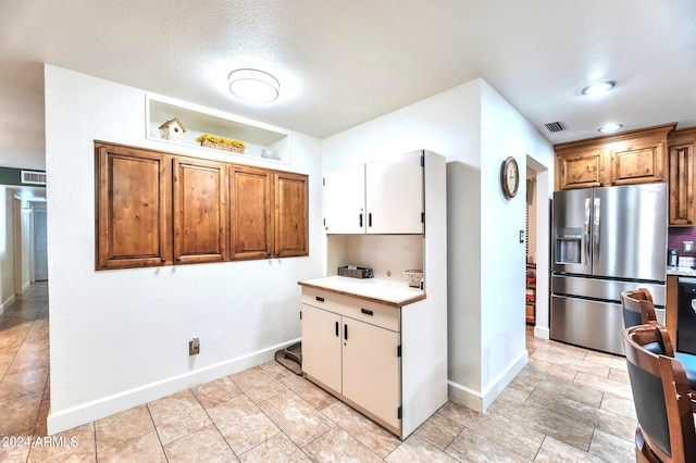 kitchen featuring stainless steel refrigerator with ice dispenser and a textured ceiling