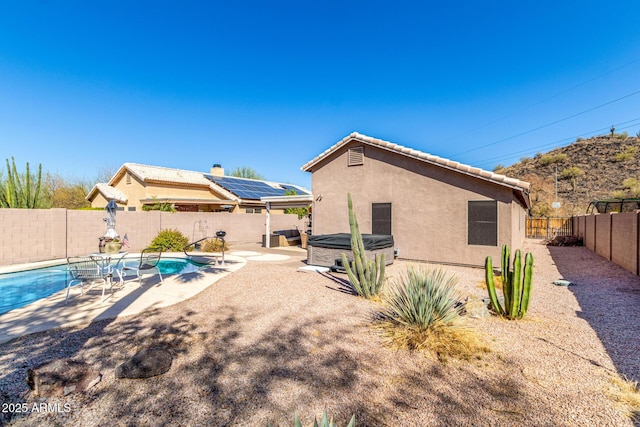 back of house with a patio, stucco siding, a hot tub, a fenced backyard, and a tiled roof