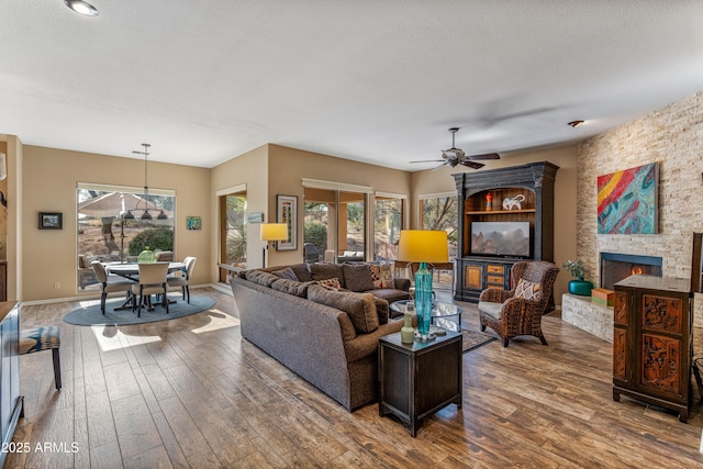 living room featuring ceiling fan, hardwood / wood-style floors, a textured ceiling, and a fireplace