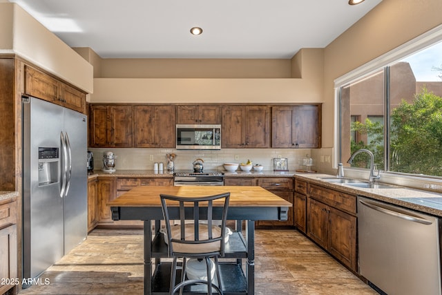 kitchen featuring appliances with stainless steel finishes, butcher block countertops, sink, backsplash, and light hardwood / wood-style flooring